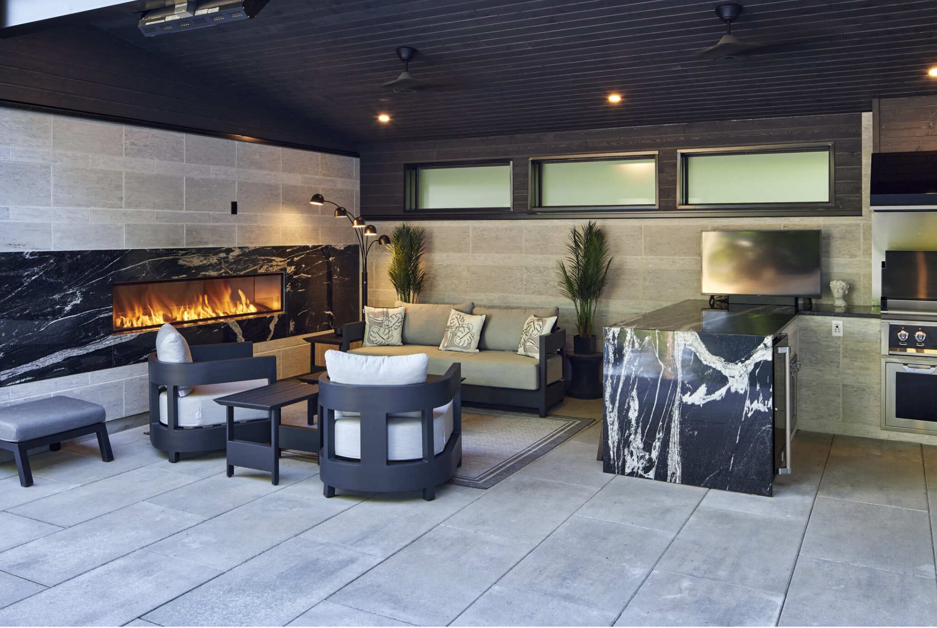 Outdoor living space with kitchen, outdoor seating, and pool by Mallette Landscaping